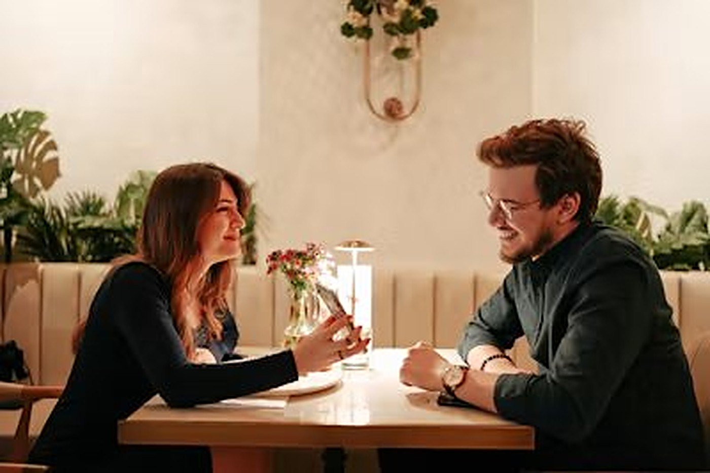 A woman and a man smiling at each other across a restaurant table