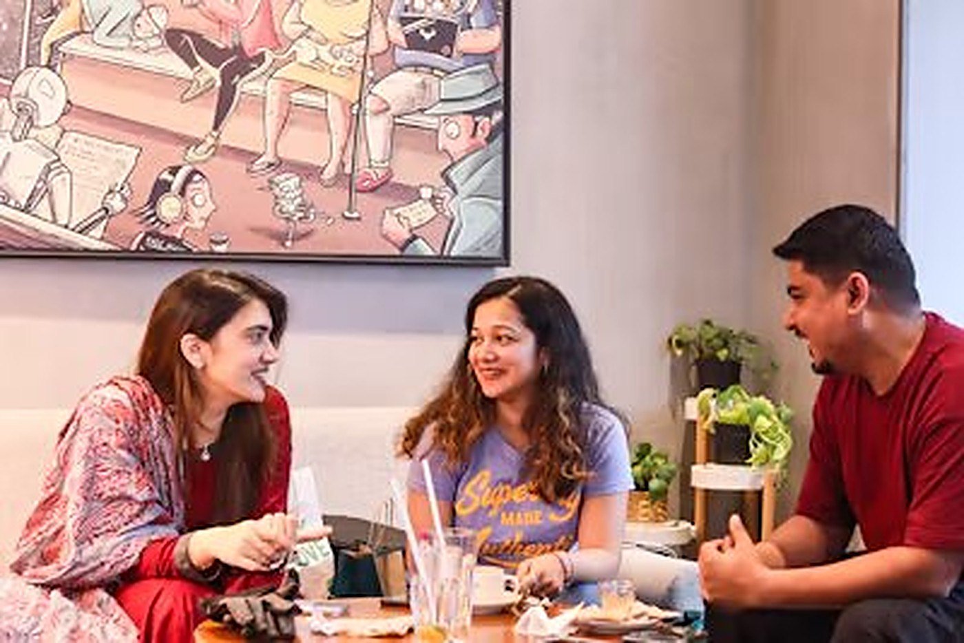 Three friends talking and laughing together in a café
