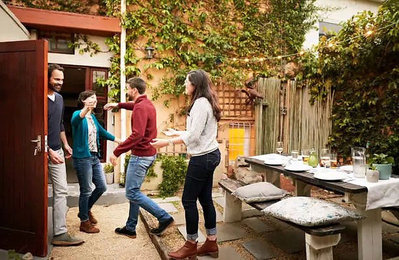 Friends greeting each other as they arrive for a garden dinner