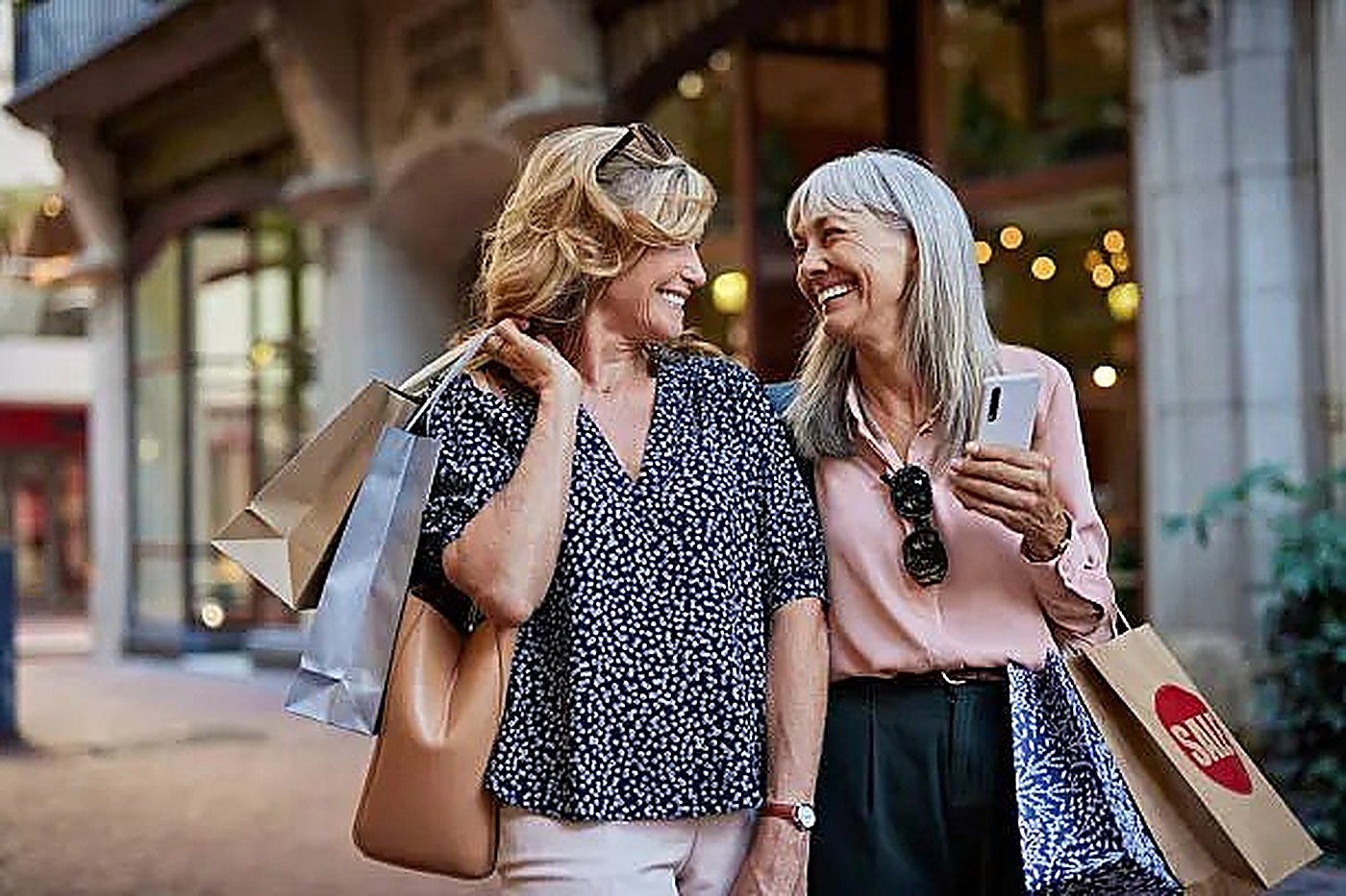 Two friends laughing together with their shopping bags