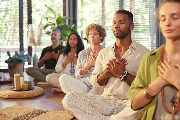 A group meditating together with hands on their hearts