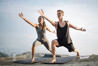 Two partners holding a yoga pose together outdoors