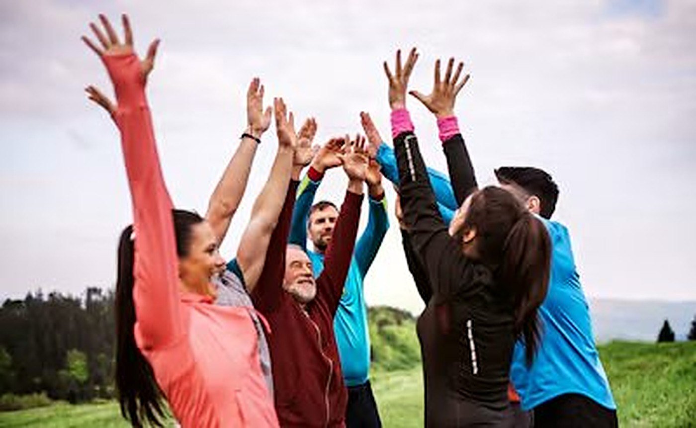 A walking group raising their hands together outdoors